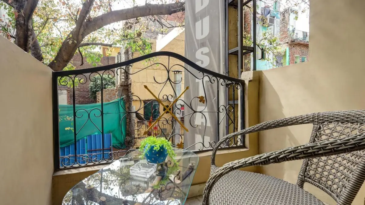 The balcony of a room, with a table, two armchairs and a tree