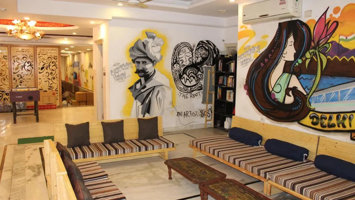 The common lounge at Hindustan by Backpackers Heaven, with wooden benches and a mural of Delhi